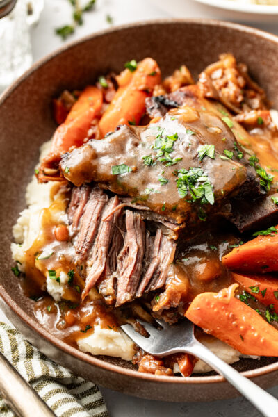 short rib served in a bowl with carrots and mashed potatoes