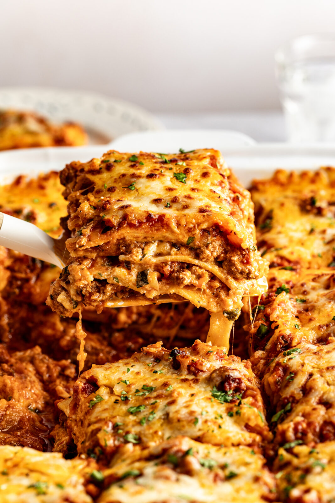 lifting slice of lasagna out of the casserole dish