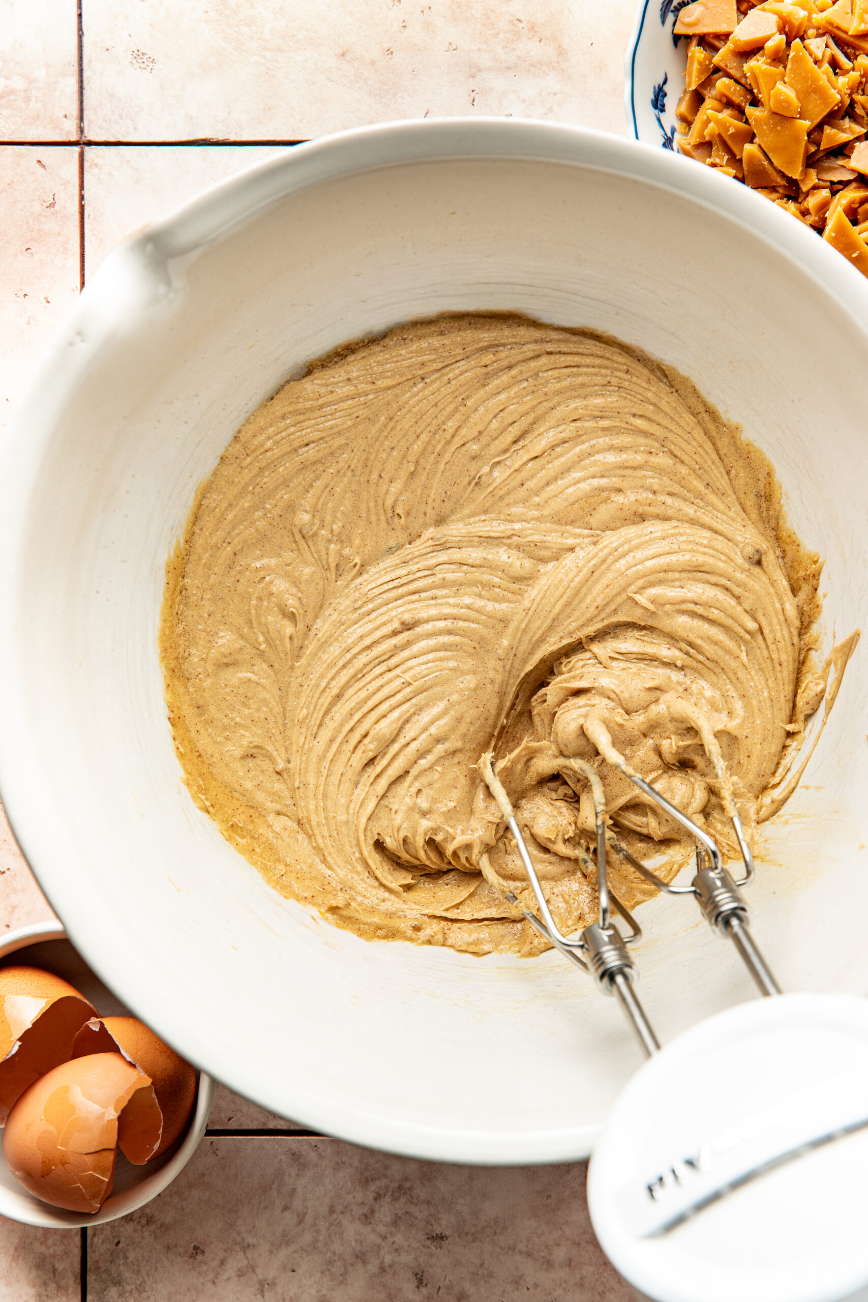 toffee cookie batter mixed in a bowl with a hand beater