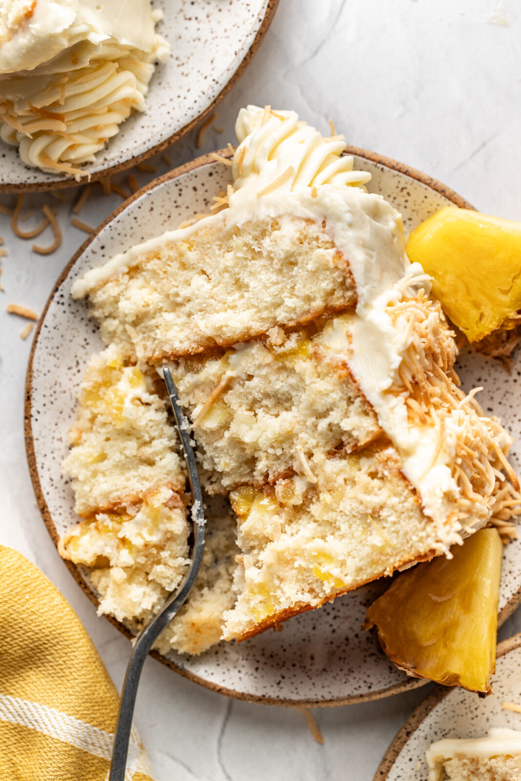 cutting into a slice of pineapple coconut cake