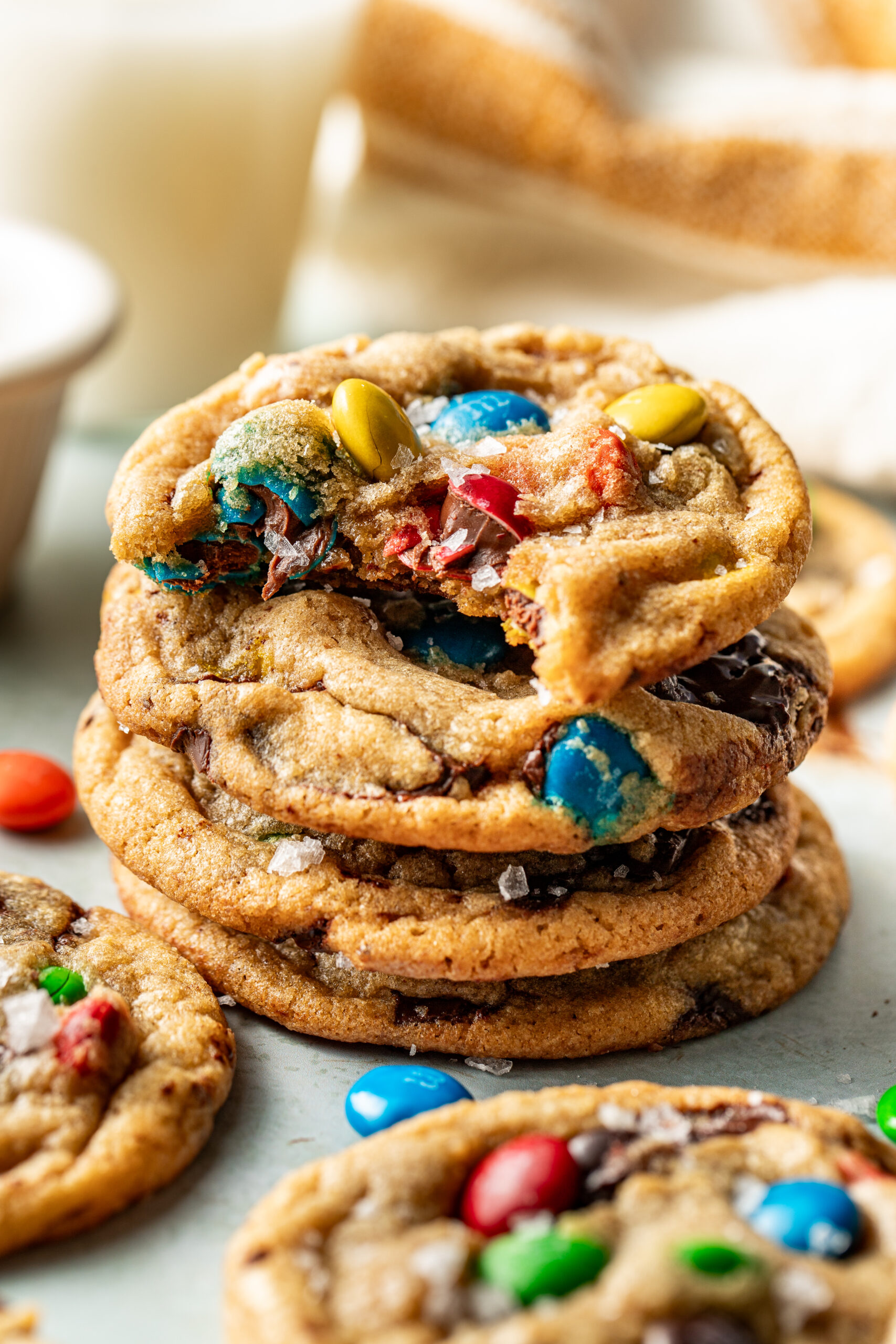 m&m cookie with a bite taken out, stacked on top of 2 cookies