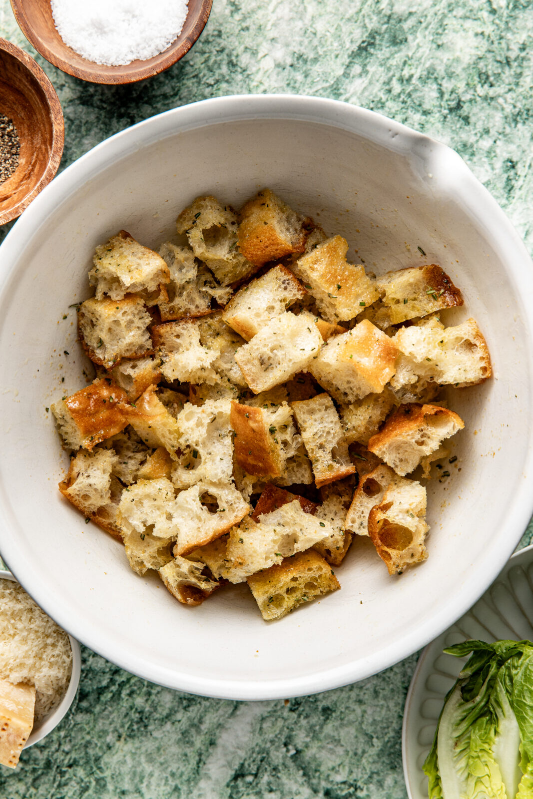 cut focaccia bread in bowl with oil and seasonings